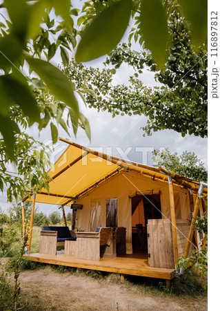 Cozy open glamping tent with light inside. Camping tent for outdoor summer holiday and vacation Cozy open glamping tent with light inside. Camping tent for outdoor summer holiday and vacation 116897812