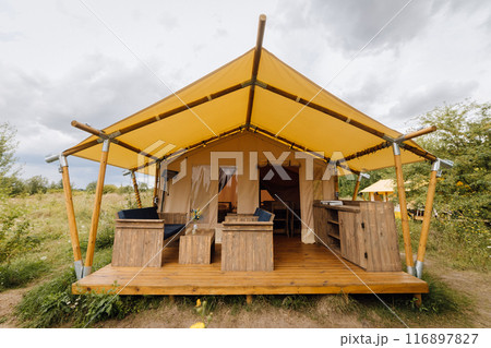 Cozy open glamping tent with light inside. Camping tent for outdoor summer holiday and vacation Cozy open glamping tent with light inside. Camping tent for outdoor summer holiday and vacation 116897827