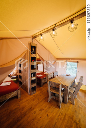 Interior of cozy open glamping tent. Camping tent for outdoor summer holiday and vacation Interior of cozy open glamping tent. Camping tent for outdoor summer holiday and vacation 116897830