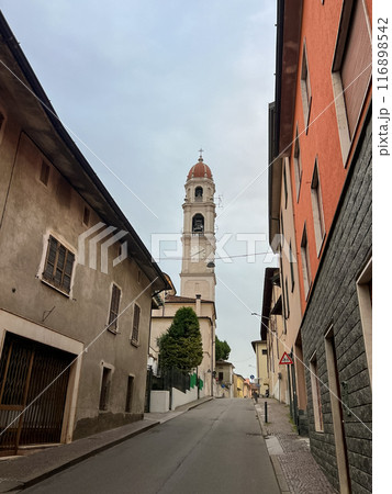 Pontevico, Italy. Deserted street in an italian town with old houses and belfry of old church 116898542