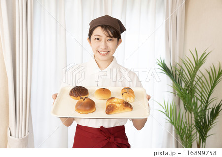 焼きたてのパンを持つベーカリーの女性スタッフ 116899758