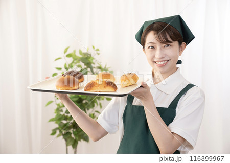 焼きたてのパンを持つベーカリーの女性スタッフ 116899967