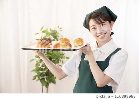 焼きたてのパンを持つベーカリーの女性スタッフ 焼きたてのパンを持つベーカリーの女性スタッフ 116899968