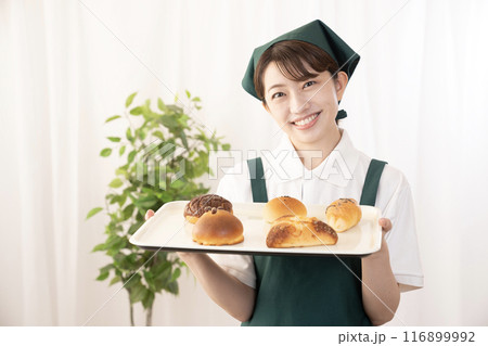 焼きたてのパンを持つベーカリーの女性スタッフ 焼きたてのパンを持つベーカリーの女性スタッフ 116899992