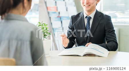 パンフレット・カタログを使い女性客と商談する若いアジア人ビジネスマン（自動車・保険） 116900124