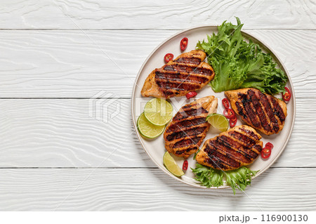grilled chicken breasts wrapped in bacon on plate 116900130