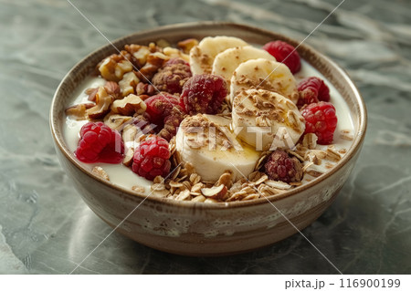 Breakfast bowl with greek yogurt topped muesli, raspberries, nuts and banana on grey concrete background, delicious and healthy food for body 116900199