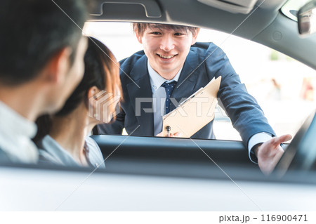 自動車購入・査定・買取にきた顧客を接客するセールスマンの若いアジア人男性 自動車購入・査定・買取にきた顧客を接客するセールスマンの若いアジア人男性 116900471