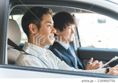 教習所で運転免許を取得するため受講する中年の男性ドライバーと教官の男性 116900756