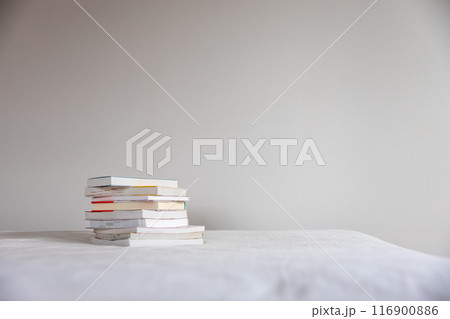 ベッドの上に重ねて置いてあるたくさんの本 116900886