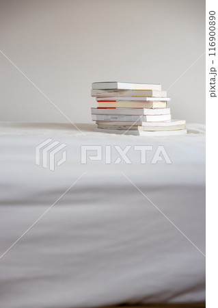 ベッドの上に重ねて置いてあるたくさんの本 116900890