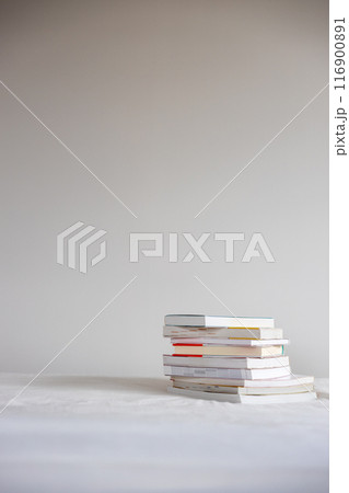 ベッドの上に重ねて置いてあるたくさんの本 116900891