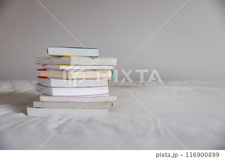 ベッドの上に重ねて置いてあるたくさんの本 116900899