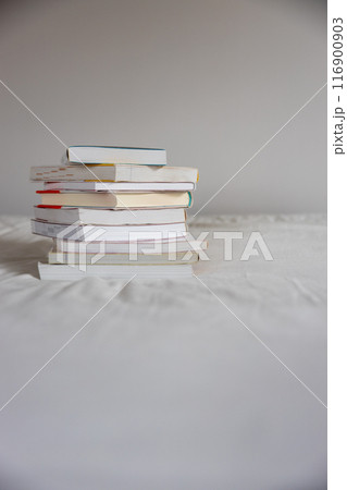 ベッドの上に重ねて置いてあるたくさんの本 116900903