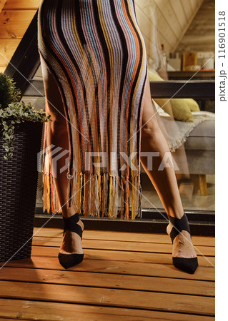 Silhouette of female legs in high heel shoes and knit beach dress 116901518