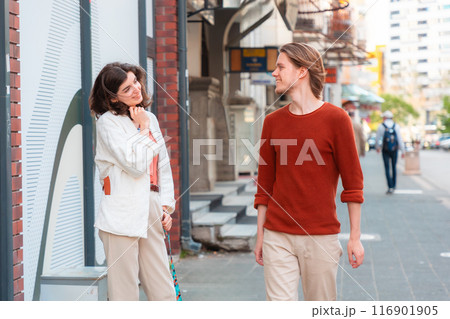 Young Caucasian woman looks at handsome smiling young man passing by on street. Psychology of relationship 116901905