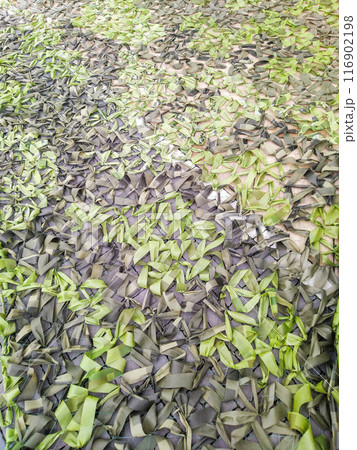 Weaving camouflage nets. Protective green textile background made of multi color ribbons. Military net 116902198