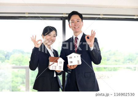 住宅模型を持ちOKをするスーツ姿の男女のビジネスパーソン 住宅模型を持ちOKをするスーツ姿の男女のビジネスパーソン 116902530