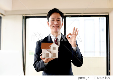 住宅模型を持ちOKをするスーツ姿の男性のビジネスパーソン 住宅模型を持ちOKをするスーツ姿の男性のビジネスパーソン 116903109