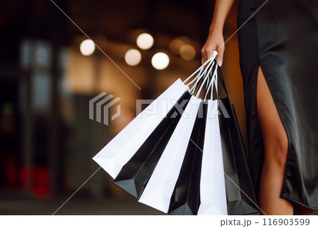 Shopping bags in the hands. Fashion woman with packages after shopping. Black friday, sale. 116903599