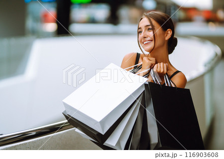 Elegant brunette woman in black dress enjoying shopping in the mall. Spring Style. Consumerism. 116903608