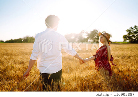 Young happy couple hugging on a wheat field, on the sunset. Enjoying time together. Young happy couple hugging on a wheat field, on the sunset. Enjoying time together. 116903887