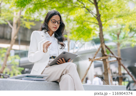 Business Young people. Asian Indian working women smart girl with tablet green park outdoor. Business Young people. Asian Indian working women smart girl with tablet green park outdoor. 116904374