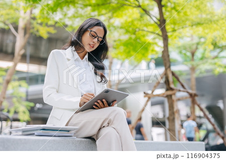 Business Young people. Asian Indian working women smart girl with tablet green park outdoor. Business Young people. Asian Indian working women smart girl with tablet green park outdoor. 116904375