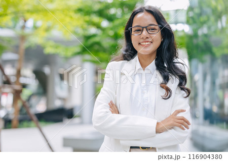 portrait Indian business women female standing happy smile. businesswomen arm folded happy in green city outdoors. portrait Indian business women female standing happy smile. businesswomen arm folded happy in green city outdoors. 116904380