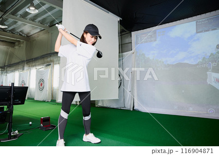 室内ゴルフ練習場で練習をする女性 116904871