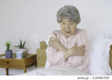 寝室で身体を抑えるシニア女性 116906390