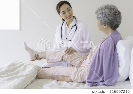 寝室で女医から膝の診察を受けるシニア女性 寝室で女医から膝の診察を受けるシニア女性 116907210