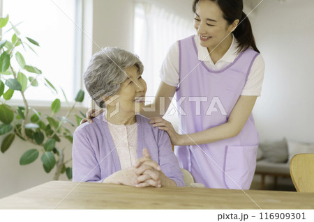 リビングで会話するシニア女性と看護師 116909301