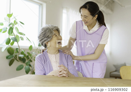 リビングで会話するシニア女性と看護師 リビングで会話するシニア女性と看護師 116909302