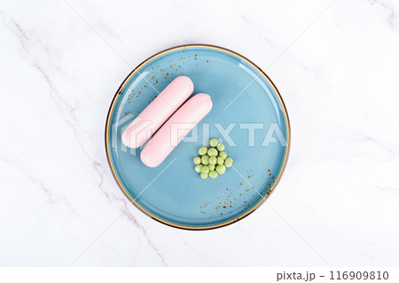 Top view of green peas and boiled sausages on a plate. 116909810