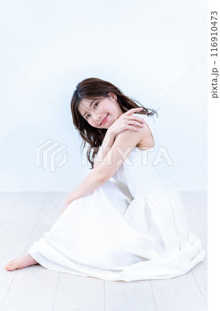 フローリングに座る白ワンピースの若い女性 フローリングに座る白ワンピースの若い女性 116910473