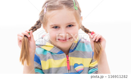 Smiling adorable school age girl playing with her well-done braided pigtail haircut, on white background Smiling adorable school age girl playing with her well-done braided pigtail haircut, on white background 116911282