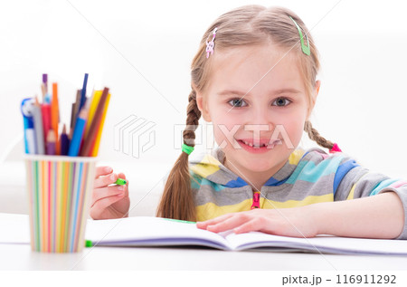 Little lovely funny girl playing with colorful markers at the working table, on white background Little lovely funny girl playing with colorful markers at the working table, on white background 116911292