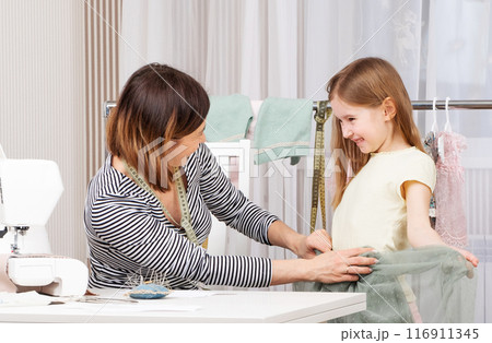 mother and daughter sew clothes in the workshop 116911345