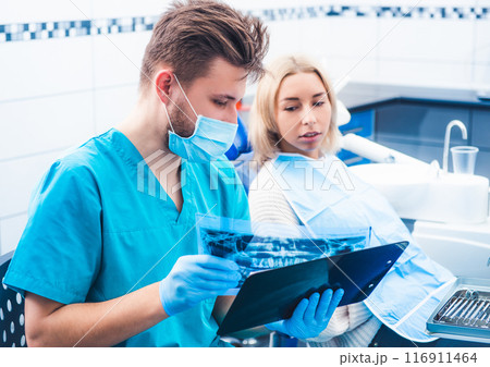Dentist in mask showing patient dental x-ray 116911464