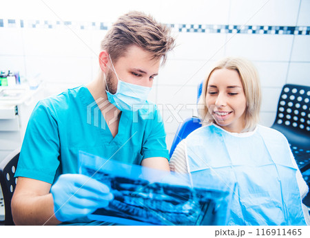Dentist in mask showing patient dental x-ray 116911465