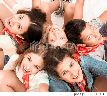 teenagers sitting on the floor with hands up smiling at camera, top view 116911901