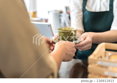 カウンターでコーヒーを手渡しする店員 116911913