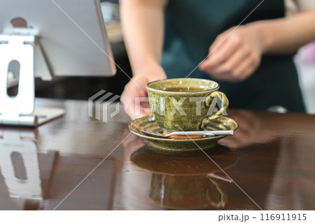 カウンターでコーヒーを手渡しする店員 116911915