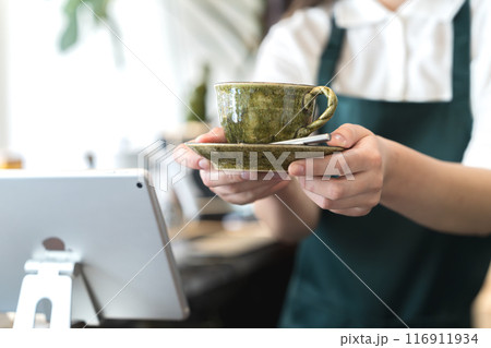 カウンターでコーヒーを手渡しする店員 116911934