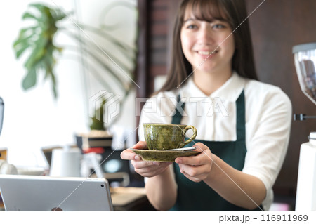 カウンターでコーヒーを手渡しする店員 116911969