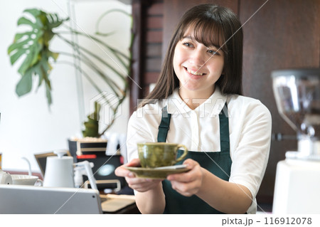 カウンターでコーヒーを手渡しする店員 116912078