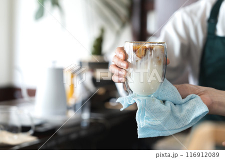 カフェオレを提供する男性の手元 116912089