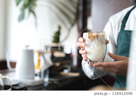 カフェオレを提供する男性の手元 116912090