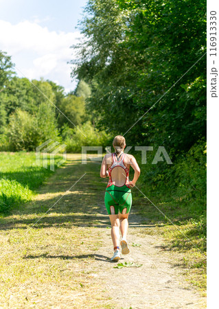 Rear view on active young man running during the triathlon competition. 116913330